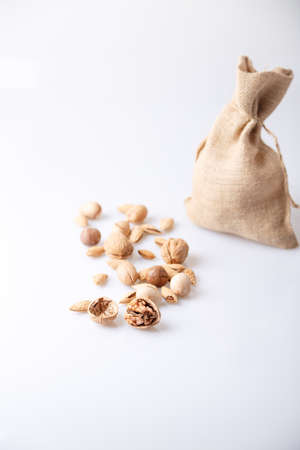 Assorted nuts in the shell on a white background: walnuts, pecans, almonds, macadamia. Nuts in a...