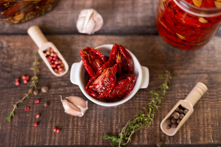Sun-dried tomatoes in olive oil in a white bowl with pepper, garlic and thyme in a rustic style. Selective focus, close-up.の写真素材