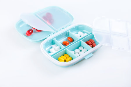 Pill box with colorful pills and vitamins. Plastic blue container with cells for medicines. health concept. Selective focus, close-up.の写真素材