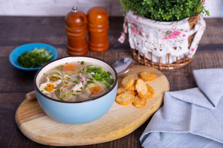 Soup with chicken, noodles, potatoes, quail eggs and carrots. Seasoned with onions and parsley. Close-up.の写真素材
