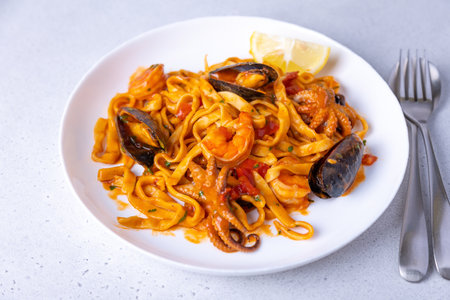 Marinara pasta with shrimps, octopus and mussels. Homemade noodles with seafood in tomato sauce. Traditional Italian dish. Selective focus, close-up.の写真素材
