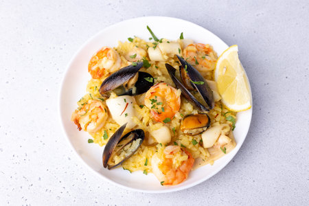 Seafood risotto with saffron, parsley and lemon. Arborio rice with tiger prawns, mussels and squid. Traditional Italian dish. Close-up, selective focus.の写真素材
