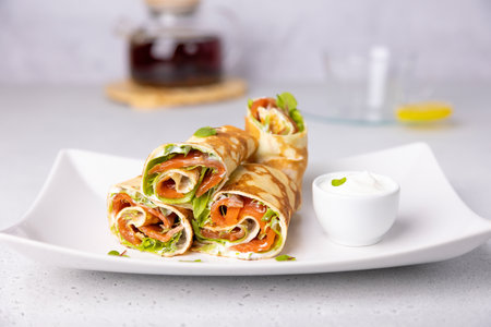 Pancakes with salmon (trout), sour cream, greenstuff and tea. Thin, not sweet blinchiki stuffed with red fish. Traditional Russian and Ukrainian dish. Feast of Maslenitsa. Selective focus, close-up.の写真素材