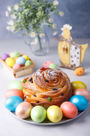 Craffin (Cruffin) with raisins and candied fruits sprinkled with powdered sugar. Traditional Easter Bread Kulich and painted eggs on a gray background. Easter Holiday. Close-up, selective focus.の写真素材