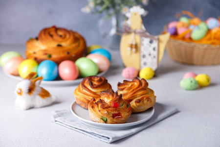 Craffin mini (Cruffin) with raisins and candied fruits. Traditional Easter Bread Kulich. In the background is a large cruffin and painted eggs on a gray background. Easter Holiday. selective focus.の写真素材