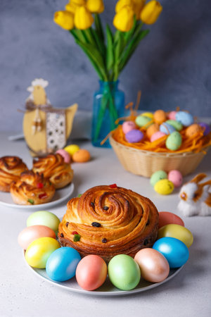 Craffin (Cruffin) with raisins and candied fruits. Traditional Easter Bread Kulich and painted eggs on a gray background. Easter Holiday. Close-up, selective focus.の写真素材