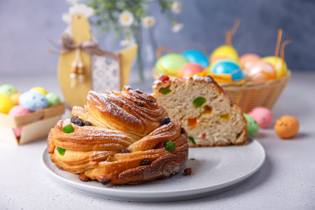 Craffin (Cruffin) with raisins and candied fruits sprinkled with powdered sugar. Traditional Easter Bread Kulich and painted eggs on a gray background. Easter Holiday. Close-up, selective focus.の写真素材