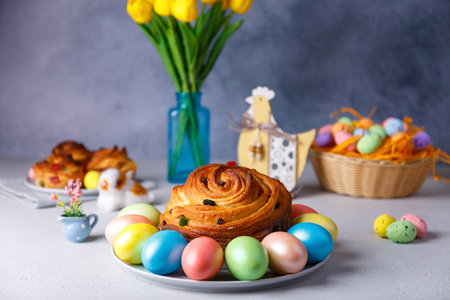 Craffin (Cruffin) with raisins and candied fruits. Traditional Easter Bread Kulich and painted eggs on a gray background. Easter Holiday. Close-up, selective focus.の写真素材