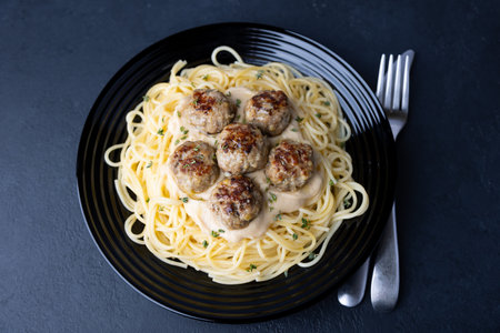 Swedish noisettes (fricandel) with spaghetti and Brune Sos creamy sauce. Traditional meatballs with garnish. Selective focus, top view, close-up.の写真素材
