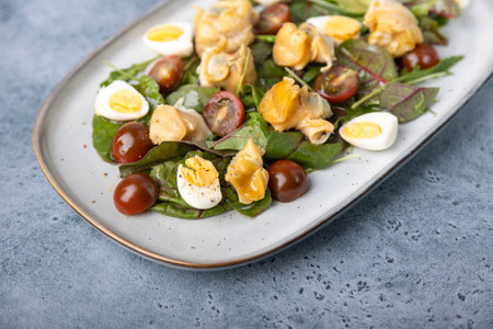 Warm salad with rapan (snails), tomatoes, cucumbers, leafy vegetables, quail eggs and olive oil. Traditional seafood salad. Close-up, selective focus.の写真素材