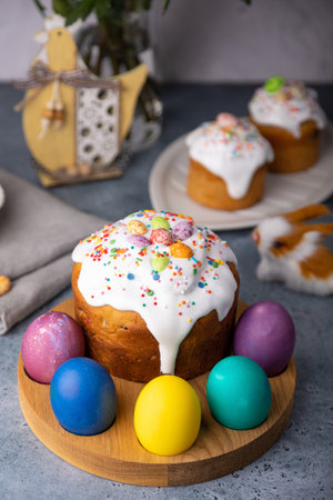 Easter kulich with candied fruits in white glaze with colorful sprinkles and painted eggs....