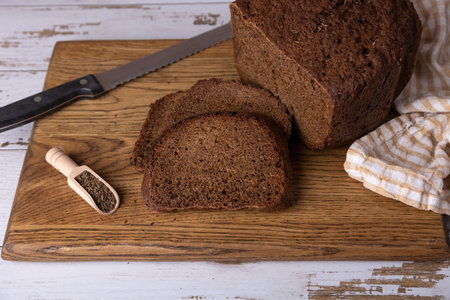 Rye Borodino (Borodinskiy) bread with a crispy crust on a wooden board, cut into slices. Homemade baking in rustic style. Selective focus, close-up.の写真素材