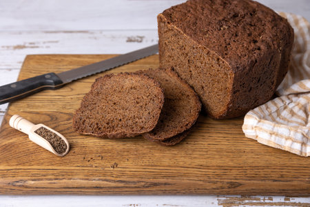 Rye Borodino (Borodinskiy) bread with a crispy crust on a wooden board, cut into slices. Homemade baking in rustic style. Selective focus, close-up.の写真素材