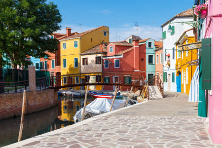 Multicolored colorful houses in Venice on the island of Burano. Narrow canal with motor boats along the houses. Summer sunny day. Selective focus.の写真素材