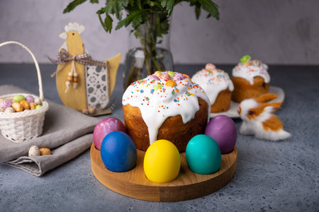 Easter kulich with candied fruits in white glaze with colorful sprinkles and painted eggs....