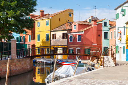 Multicolored colorful houses in Venice on the island of Burano. Narrow canal with motor boats along the houses. Summer sunny day. Selective focus.の写真素材