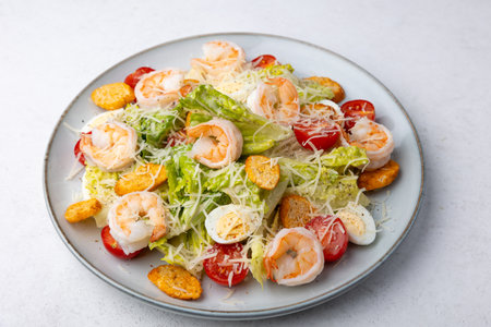 Caesar salad with tiger prawns, cherry tomatoes, croutons, parmesan cheese, quail eggs and romaine lettuce. Traditional American dish. Close-up, selective focus.の写真素材