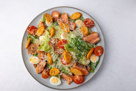 Caesar salad with trout (salmon), cherry tomatoes, croutons, parmesan cheese, quail eggs and romaine lettuce. Traditional American dish. Close-up, selective focus.の写真素材
