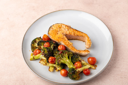 Fried salmon steak (trout) with baked broccoli and cherry tomatoes. Traditional home cooking. Selective focus, close-up.の写真素材