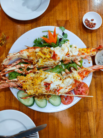 Whole grilled lobster with cheese and garlic, served with vegetables, pepper and salt. Restaurant in Nha Trang, Vietnam. Selective focus, close-up, top view.の写真素材