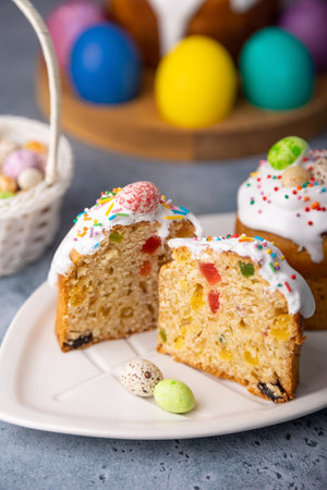 Two small Easter kulichs with candied fruits in white glaze with colorful sprinkles in the cut....