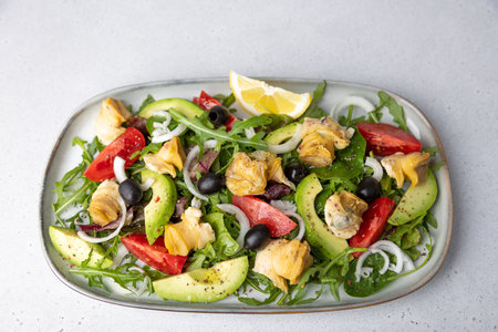 Warm salad with rapans (snails), tomatoes, avocado, arugula, black olives, onions and olive oil. Traditional seafood salad. Close-up, selective focus.の写真素材