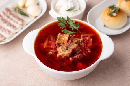Borsch with pampushki (buns), sour cream, lard and garlic. Traditional Russian and Ukrainian soup with meat, beets, cabbage and potatoes. Close-up, selective focus.の写真素材