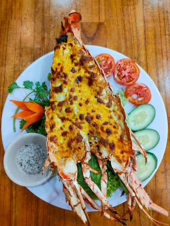 Whole grilled lobster with cheese and garlic, served with vegetables, pepper and salt. Restaurant in Nha Trang, Vietnam. Selective focus, close-up, top view.の写真素材