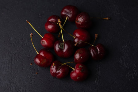 Rotten ripe cherries with mold and rotten sides on a black background. Seasonal fruits, harvest. Selective focus, close-up.の写真素材