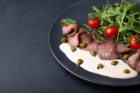 Vitello Tonnato with arugula, cherry tomatoes, capers, and parsley. A popular Italian appetizer made...