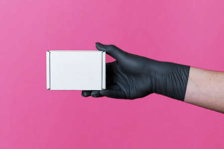 mock-up of a box of white cortona in a female hand in black medical gloves on a colored background....
