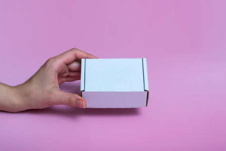 white corton box for mock-up in a female hand on a pink background. space for textの写真素材