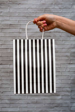 Close-up mock-up of eco-packaging on a brick gray background. Kraft bag in black and white stripes...