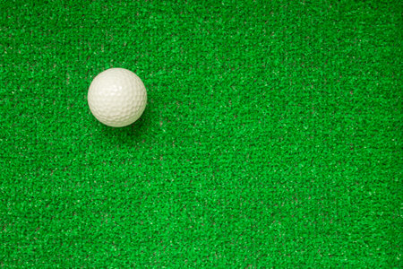 Golf ball on a green background, top view. Green decorative grass, background. Golf ball on artificial grassの写真素材