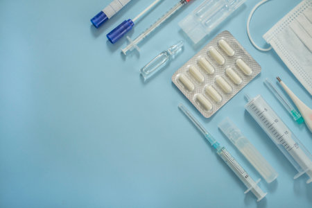 View from above. medical supplies, mask, syringe, ampoule with medicine or vaccine, thermometer, pills. Flat medical view place for textの写真素材
