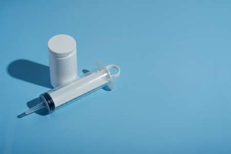 Pills, syringe for a catheter on a blue medical background. close-up, top view. Medical syringe, tube with vitaminsの写真素材