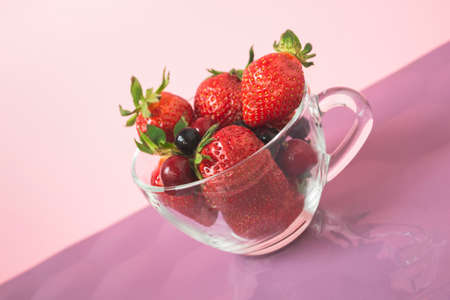 Close-up glass cup with strawberries on colored backgroundの写真素材