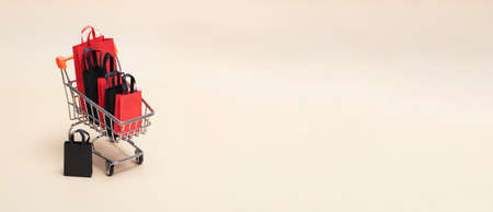 Black friday concept, mockup of paper black and red shopping bags with trolley on colored background. Black Friday sale. Bnnerの写真素材