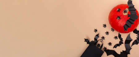 Top view on a beige background black package with flies, pumpkin and bats. Close up of a halloween party. invitation layout. Bannerの写真素材