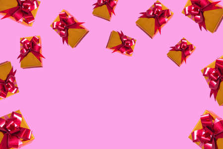 New Year Christmas composition. Gold gift with a red bow on a pink background. Top View Copy Space...