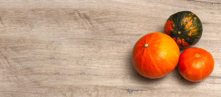 Pumpkins of different sizes and different colors on a wooden background. Thanksgiving concept, top view close up. Bannerの写真素材