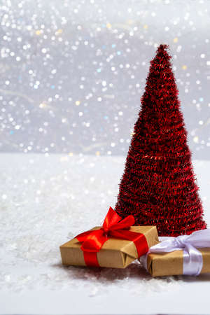 Christmas tree with gifts on the snow against a background of bright bokeh lights. Minimal concept of postcard, invitation card. Close up with copy space. Vertical photoの写真素材
