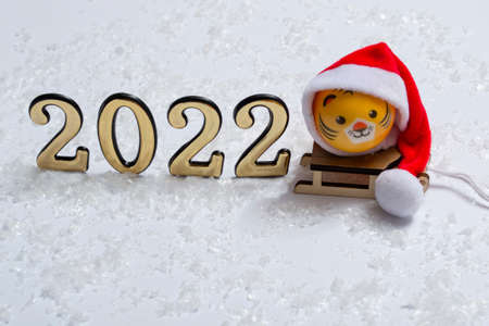 The symbol of the new year is a tiger in a Santa hat on a sleigh in the snow with golden numbers on a background of bokeh lights. New year conceptの写真素材