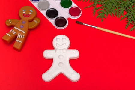 Christmas decorative gingerbread man and paints, creativity concept on a red background with a...
