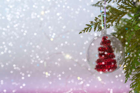 Christmas concept transparent ball with a red Christmas tree inside, close-up on a background of bokeh lights. Copy spaceの写真素材