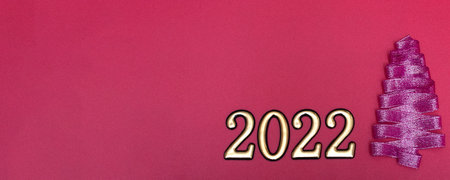 Christmas concept. Purple Christmas tree made from ribbons and gold numbers on a pink background...