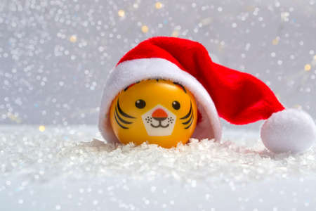The symbol of the new year is a tiger in a Santa hat on the snow against a background of bokeh lights. Close up of new year conceptの写真素材