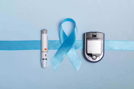 Close up top view of concept for World Diabetes Day 14 November. Blue tape with blood drops and a glucometer on a blue background.の写真素材