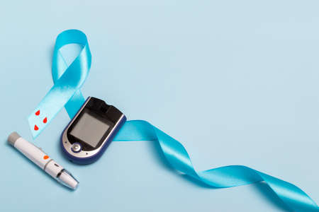 Close up top view of concept for World Diabetes Day 14 November. Blue tape with blood drops and a glucometer on a blue background. copy spaceの写真素材