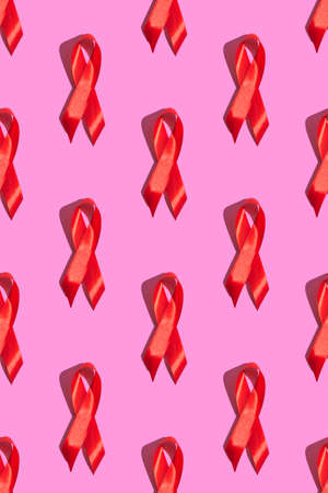 International AIDS Day. Red ribbon with a hard shadow on a pink background. AIDS awareness concept....